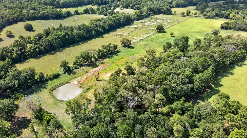 Aerial view of a pond and surrounding acreage